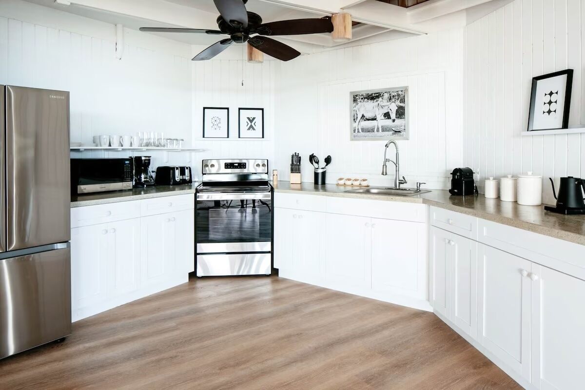 Una cocina moderna con armarios blancos, electrodomésticos de acero inoxidable y suelo de madera.