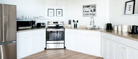 Une cuisine moderne avec des meubles blancs, des appareils en acier inoxydable et un plancher en bois.