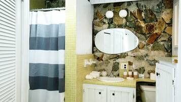 A bathroom with a stone wall, a white sink, and a mirror.