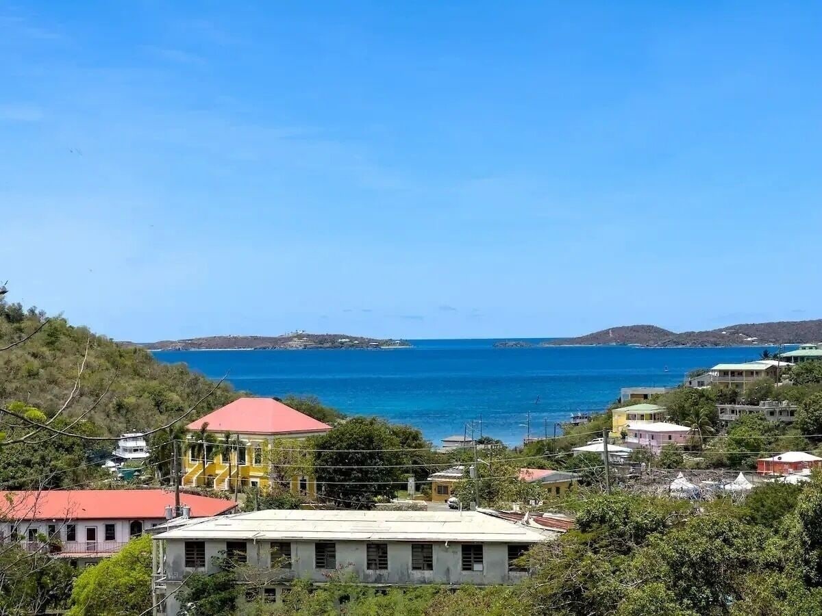 Une vue côtière avec des bâtiments, une construction au toit rouge et une mer bleue et limpide.