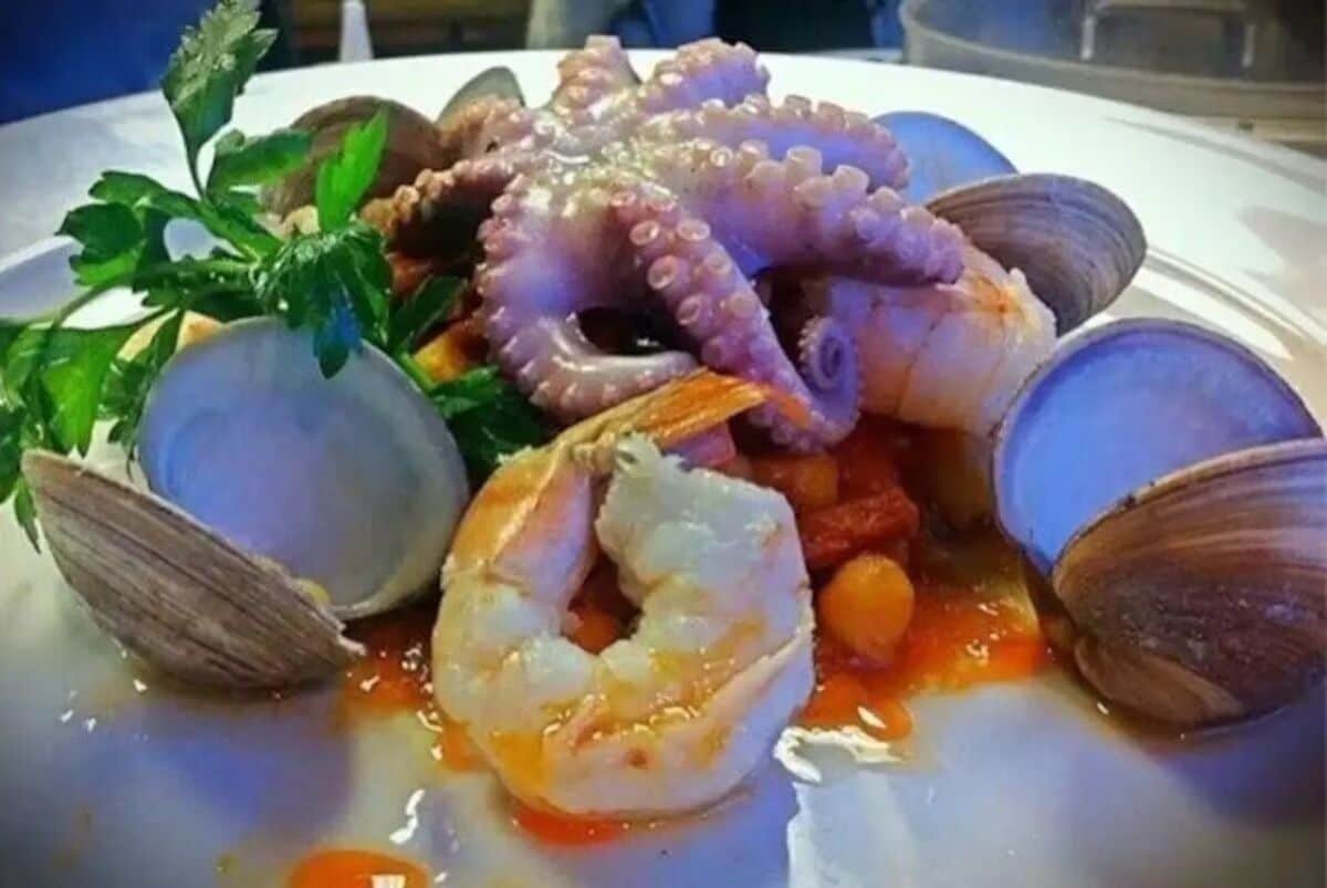 Un plato de mariscos con almejas, camarones y pulpo.