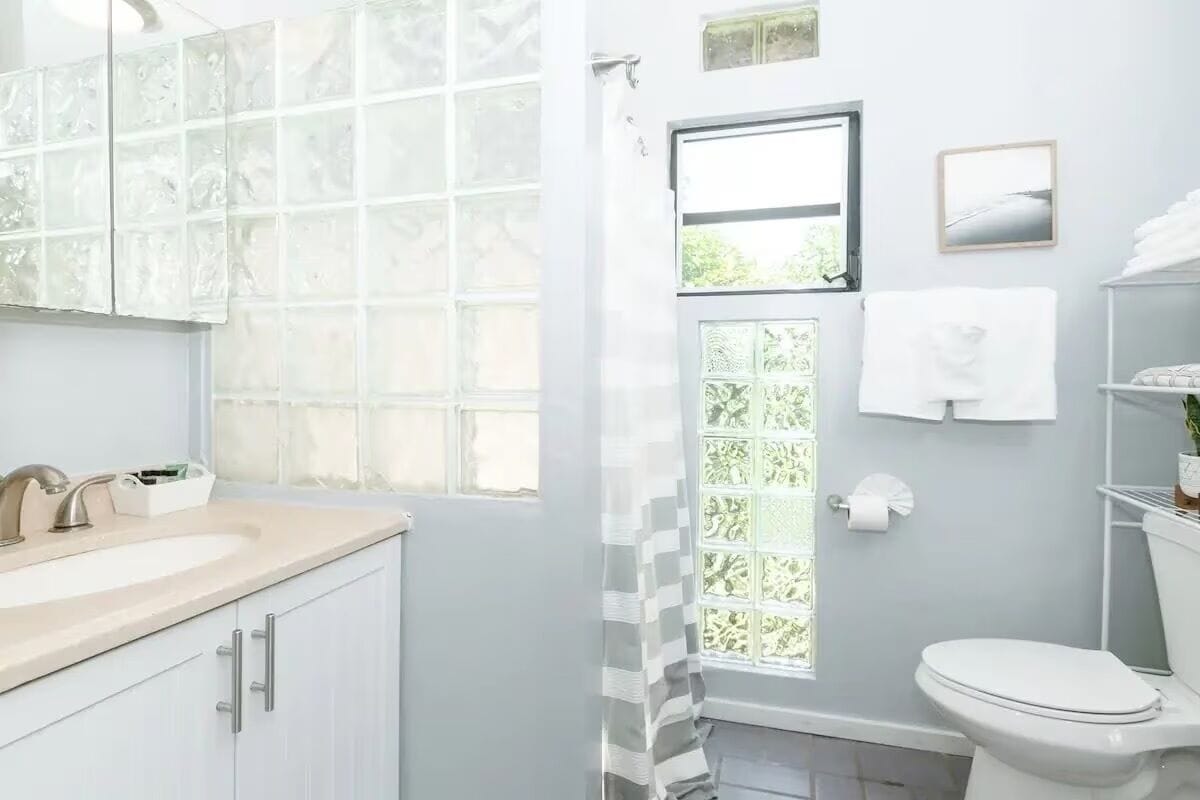 Un baño con lavamanos blanco, un espejo, inodoro y cortina de ducha.