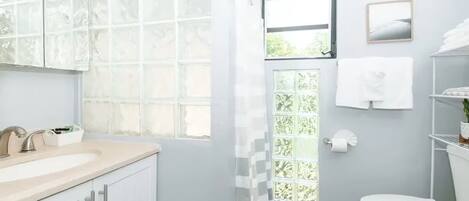 Un baño con lavamanos blanco, un espejo, inodoro y cortina de ducha.