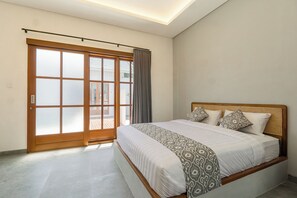 Une chambre avec un grand lit, une porte-fenêtre coulissante et un luminaire au plafond.