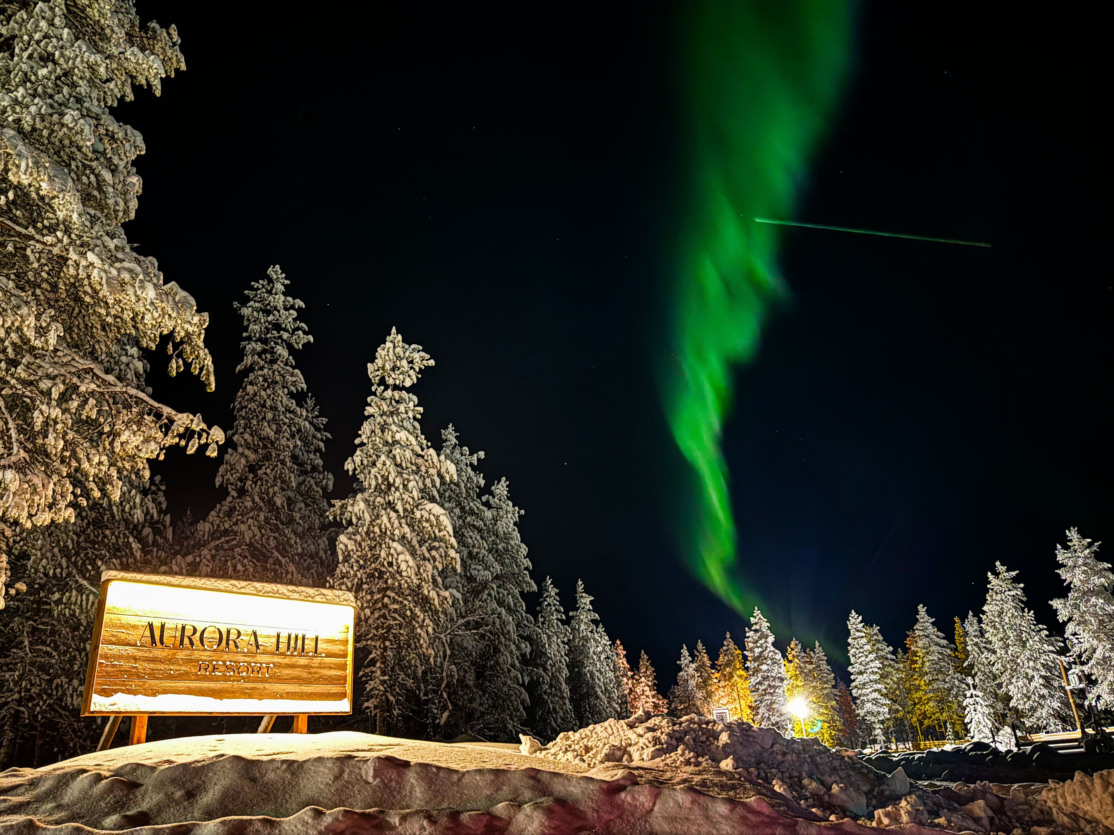 Aurora Hill Resort -kyltti, josta avautuu näkymä revontuliin.