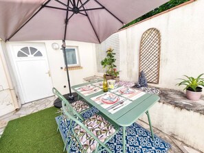 Eine Terrasse mit Esstisch, einem Blumentopf und einer Buddha-Statue.
