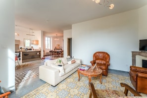 A living room with a sofa, armchairs, a coffee table, and a fireplace.