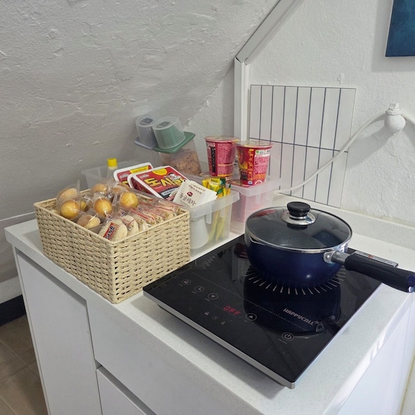 A kitchenette with a stove, a basket of bread, and various food items. - Ribini House (Seoul)