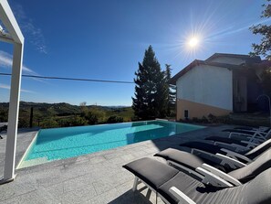 A swimming pool with lounge chairs, a clear sky, and a view of distant hills. - Relais Portaluna delle Langhe / 7BR, Sleeps 18, AC, Pool, Garden, Vineyard Views (Piemonte)