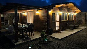Een gezellig buitenontbijtgedeelte met een tafel, stoelen, een barbecue en een kleine tuin.