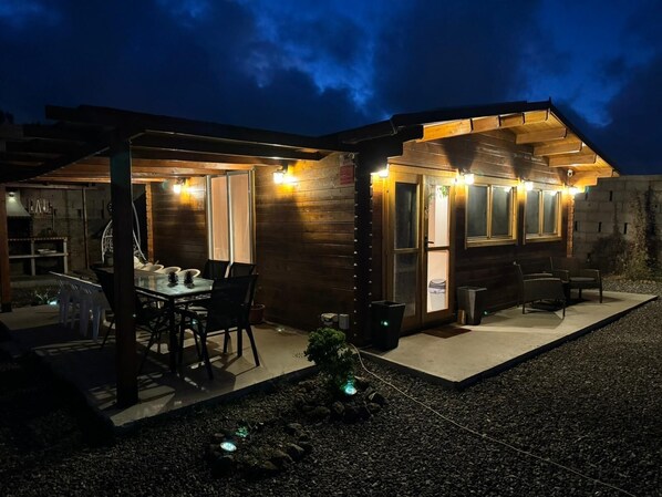A cozy outdoor dining area with a table and chairs, a grill, and a small garden. - Peaceful Getaway with Pool, Jacuzzi & BBQ Area (El Rosario)