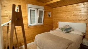 Een kamer met houten lambrisering, een bed, een raam en een ladder.