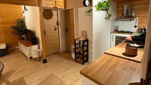Een houten interieur met een keukenhoek, een zithoekje en een deur naar een andere kamer.