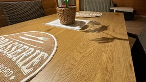 Een houten eettafel met geweven tafelonderleggers en een potplant.
