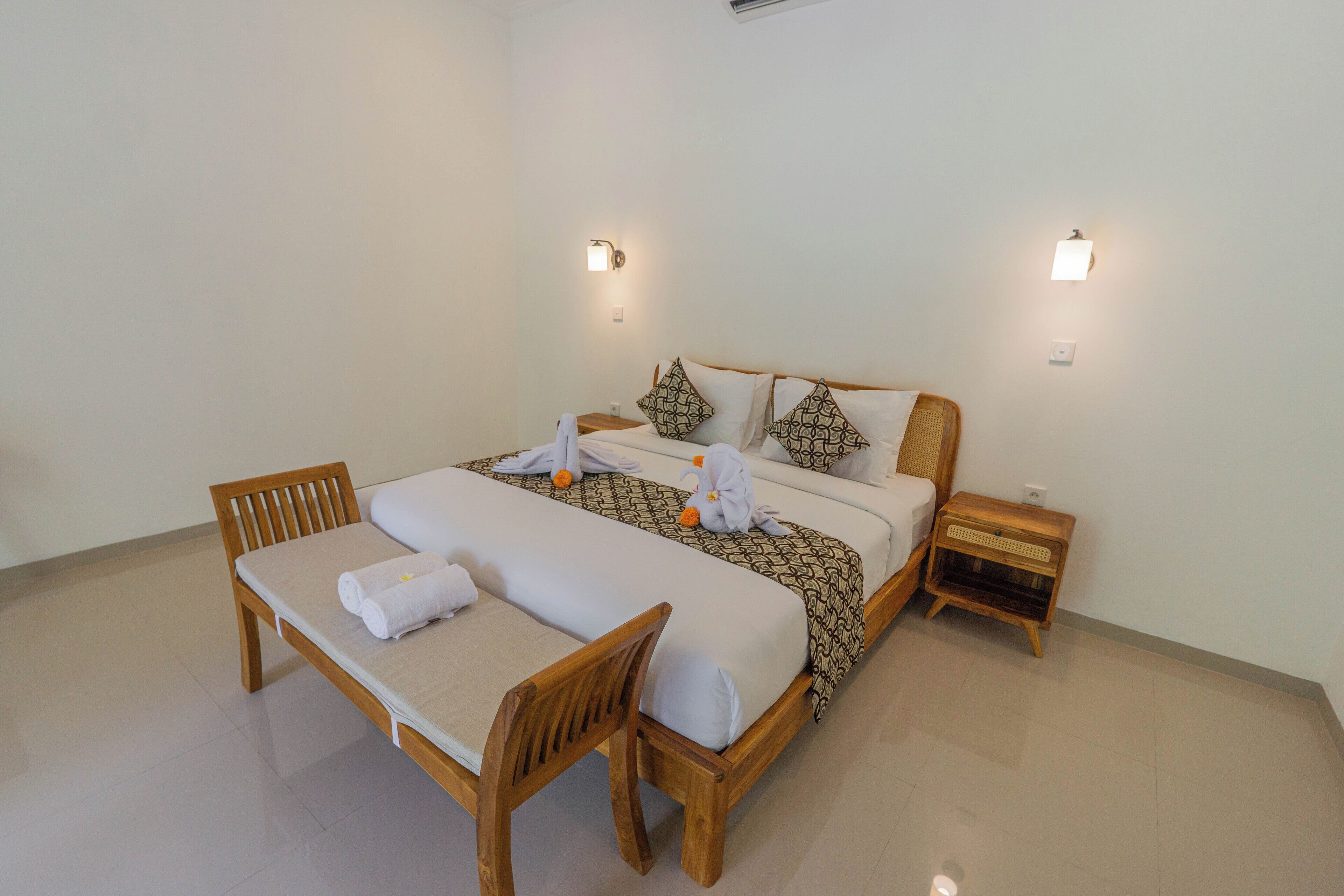 A neatly arranged bedroom with a bed, a bedside table, a chair, and two wall-mounted lights.