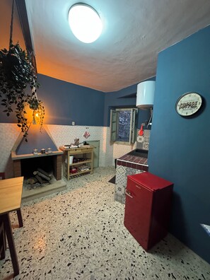 A compact kitchen with a built-in stove, a hanging plant, and a clock on the wall. - Historic & Charming Home in Bassiano (Bassiano)