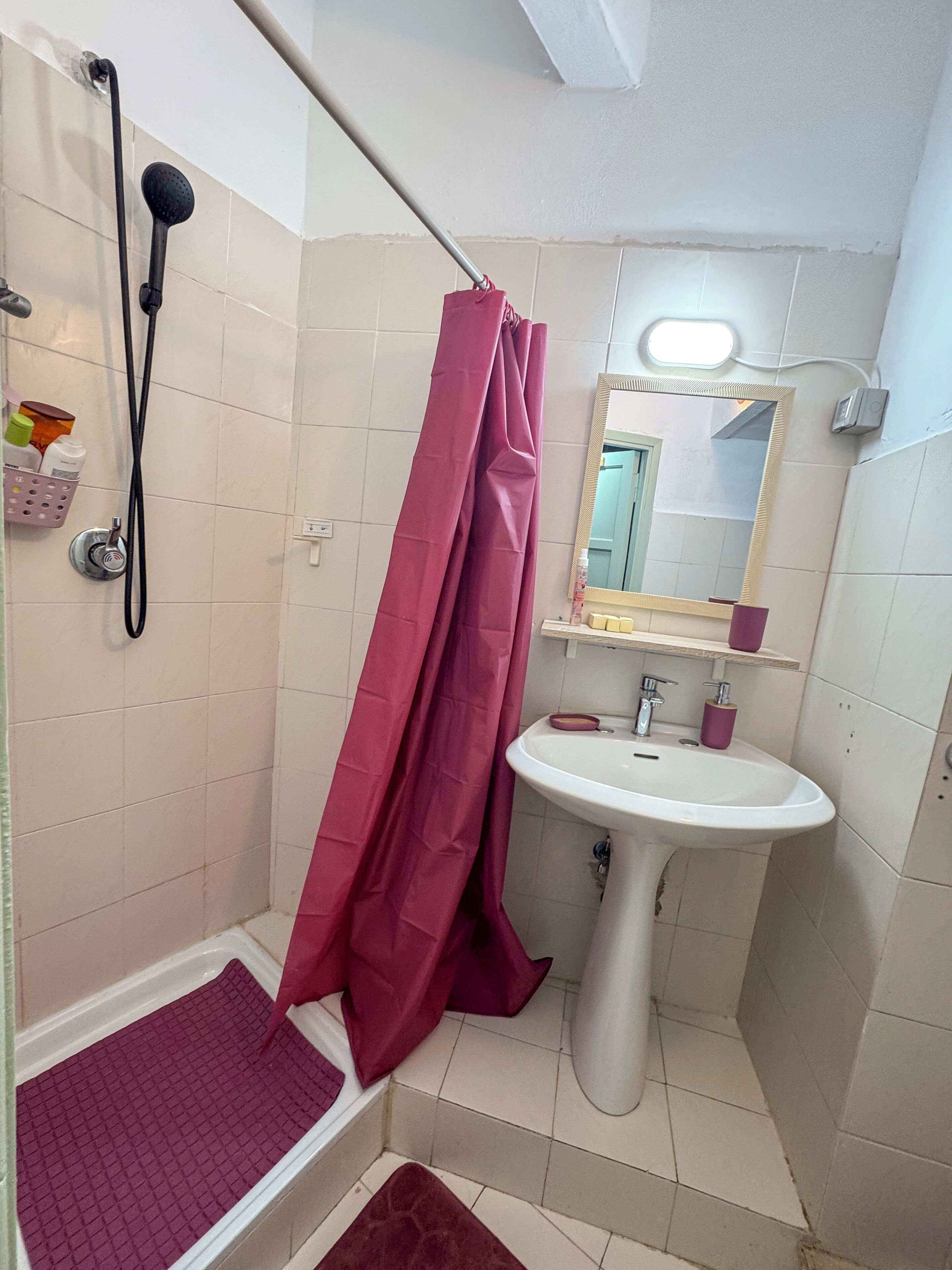 A bathroom with a shower, a sink, and a mirror.