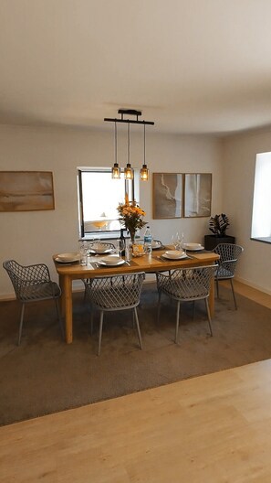 A dining area with a wooden table, wire mesh chairs, pendant lights, and artwork on the walls. - Retiro da Calheta, designed for relaxation and family time - Madeira Island (Estreito da Calheta)