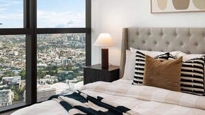 A bedroom with a large window, a bed with a tufted headboard, and a bedside table with a lamp. - Million$ Panoramic RiverView/ Casino/ Designer/CBD (Brisbane)