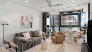 A modern living room with a sofa, armchairs, a coffee table, and a television. - Million$ Panoramic RiverView/ Casino/ Designer/CBD (Brisbane)