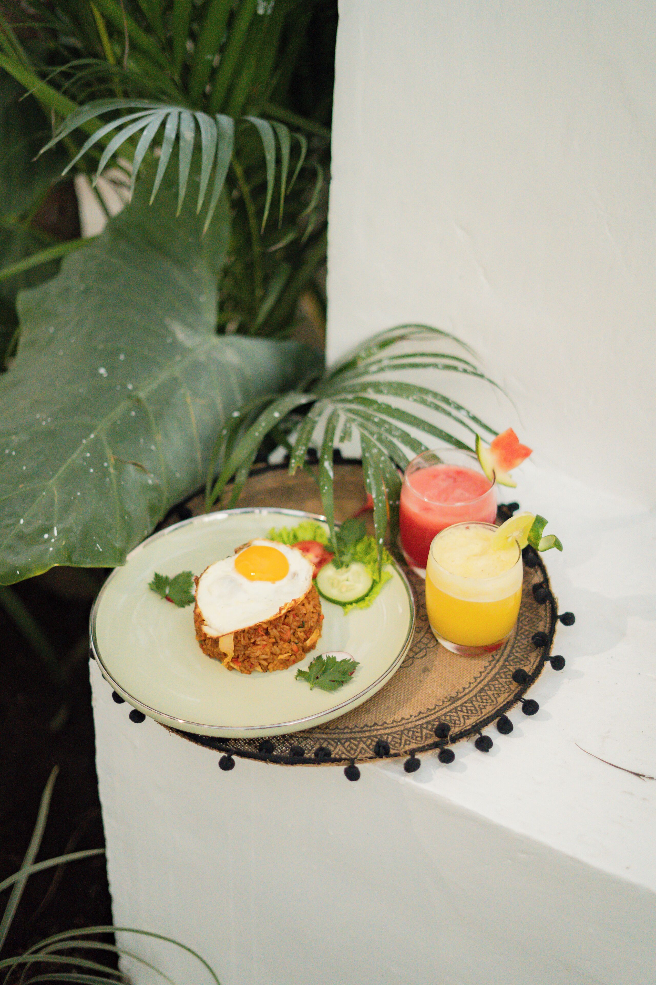 A plate with a sandwich, a glass of juice, and a slice of watermelon on a table.