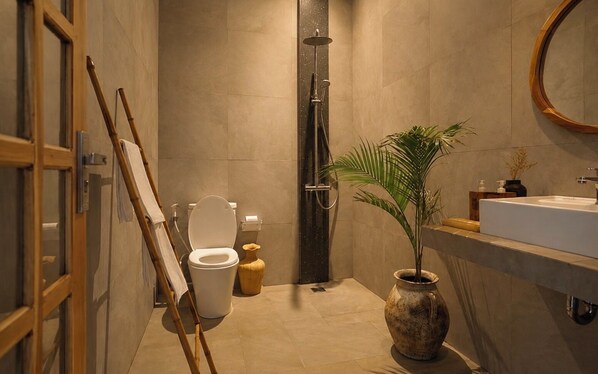 Une salle de bain avec des toilettes, une douche, un lavabo et une plante.
