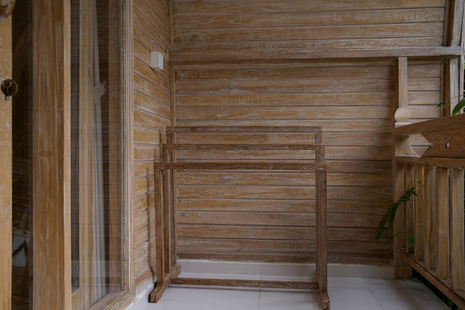 Un intérieur en bois, agrémenté d’une simple étagère en métal et d’une plante.