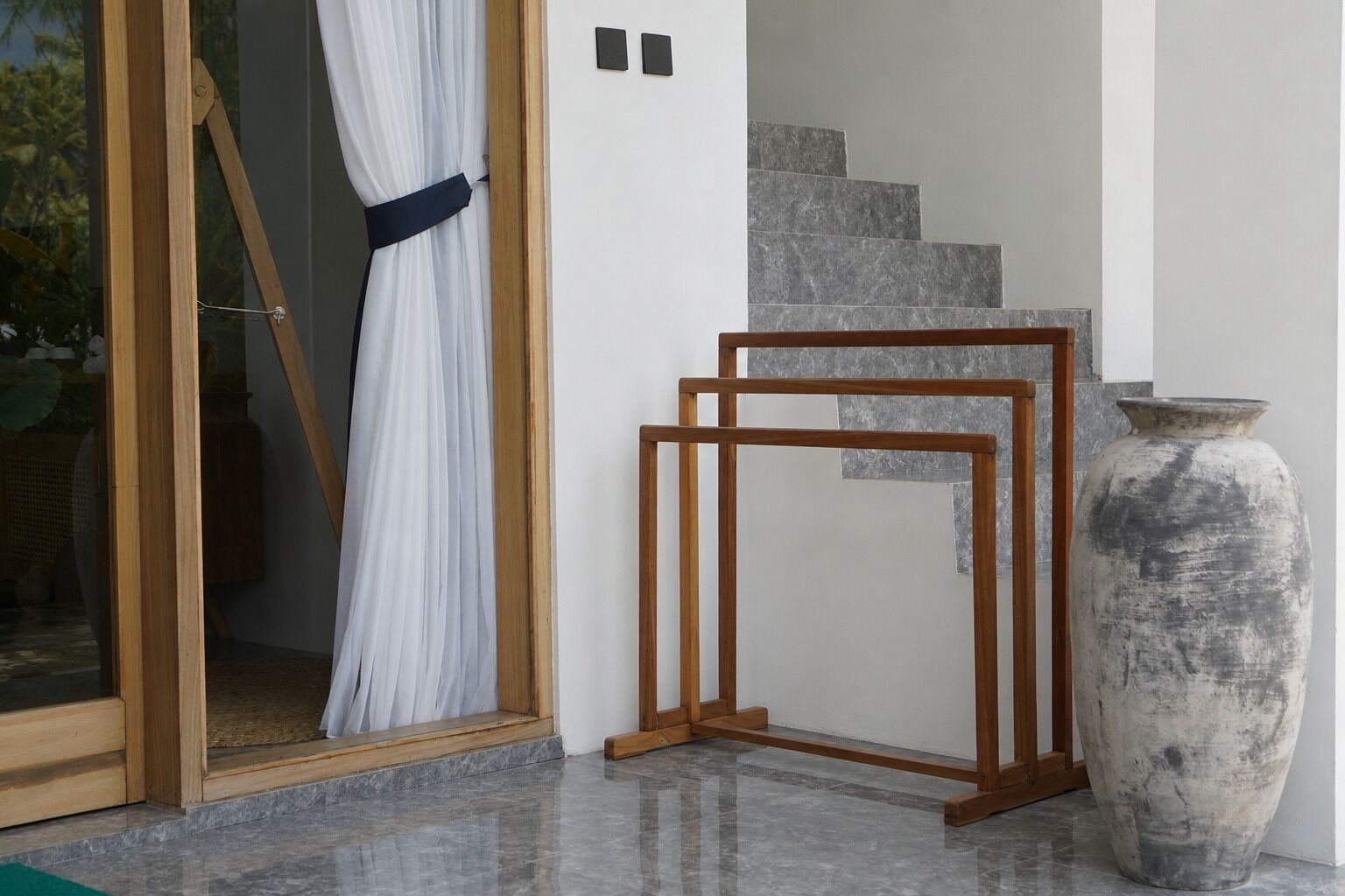 Una habitación con puerta de vidrio, estructura de madera y un jarrón grande.