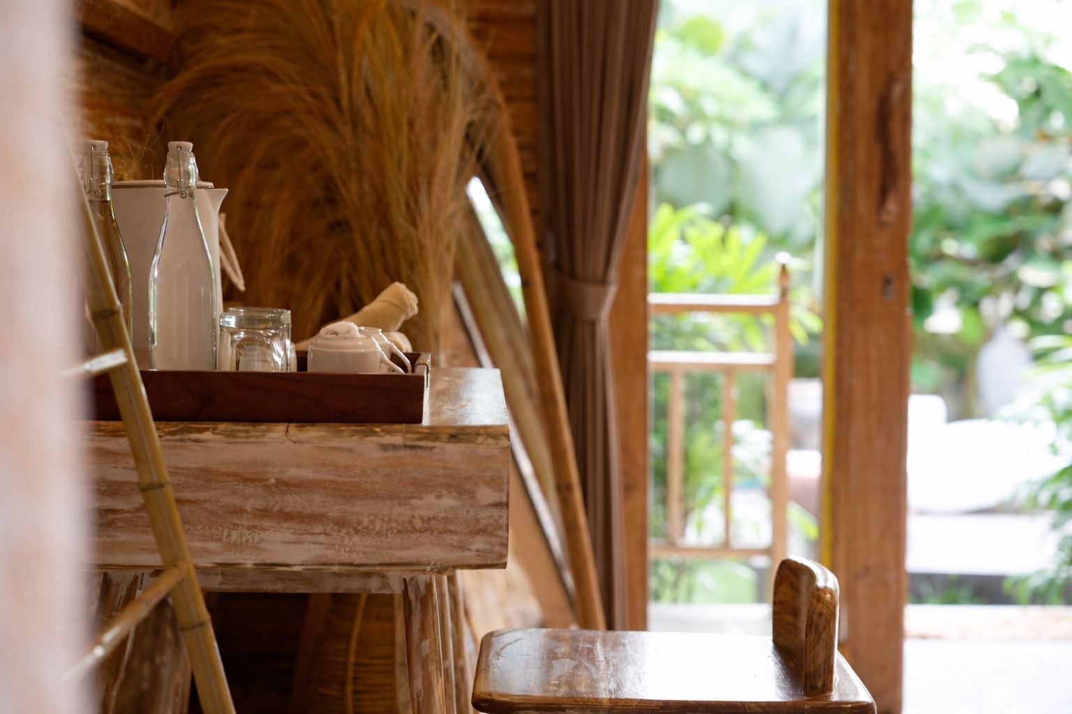 Ein rustikales Holzinterieur mit einem Holztisch, auf dem Glasflaschen, ein Teekessel und eine Ablageplatte stehen.
