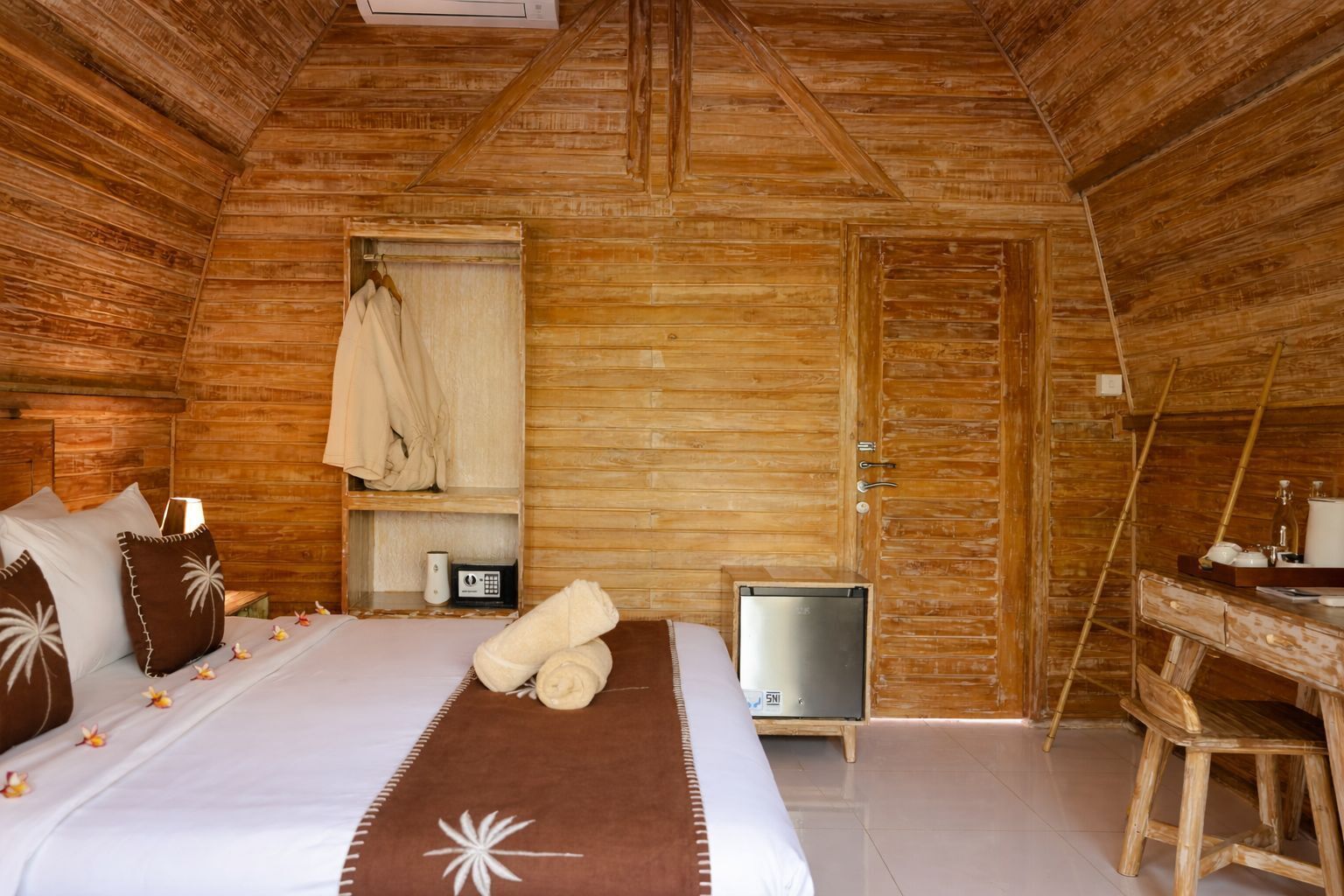Une pièce de cabane en bois comprenant un lit, une petite table, une chaise, un radiateur et une porte.