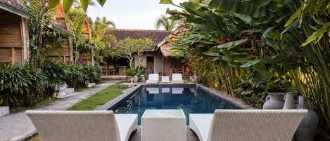 A pool area with wicker furniture and tropical plants.