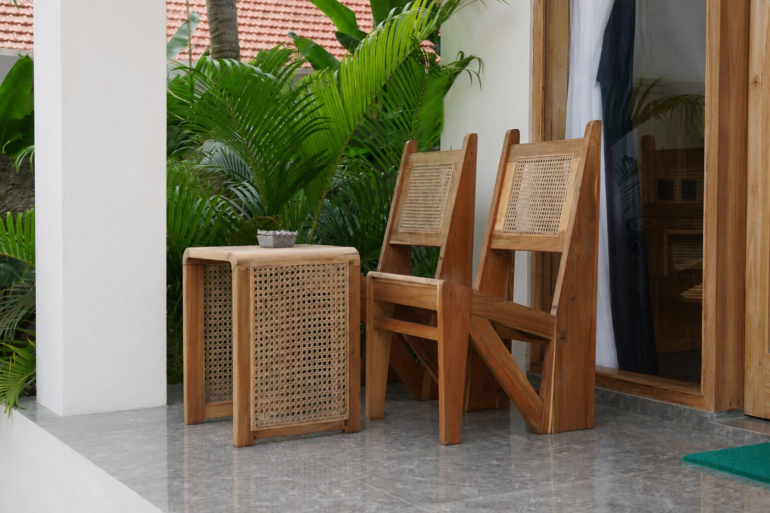 A wooden chair and table set on a tiled floor with a potted plant in the background.