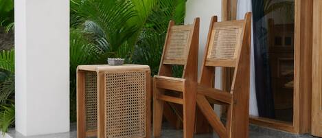 A wooden chair and table set on a tiled floor with a potted plant in the background.