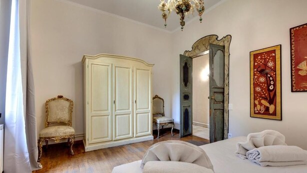 A bedroom with a bed, two chairs, a wardrobe, and a chandelier. - Spacious 5-bedroom apartment in charming Firenze with AC (Firenze)