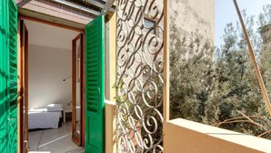 A room with a bed, a green door, and a balcony with a wrought iron railing. - Spacious 5-bedroom apartment in charming Firenze with AC (Firenze)