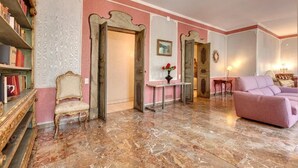 A room with a marble floor, a pink sofa, a gold chair, and a bookshelf. - Spacious 5-bedroom apartment in charming Firenze with AC (Firenze)