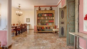 A library with a marble floor, a wooden bookshelf, and a dining area with chairs and a table. - Spacious 5-bedroom apartment in charming Firenze with AC (Firenze)