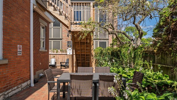 Une terrasse dotée de meubles en osier et d’un mur en briques.