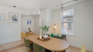 Un espace repas moderne avec une table en bois, des chaises vertes et un vase rempli de fleurs.