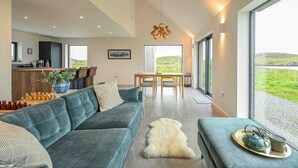 A modern living room with a sofa, a coffee table, and a view of the outdoors. - Wow sea-view! walks, cliffs, wildlife - spacious contemporary home (Portree)