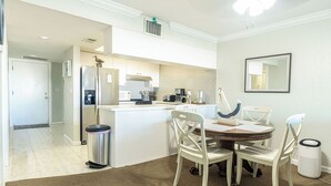 A modern kitchen with white cabinets, a central island, and a dining area with four chairs. - Lakefront Condo in Clewiston •Heated Pool•Fishing Paradise •Sleeps 4 (Clewiston)