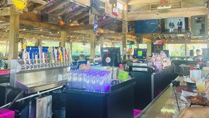 A bar with multiple TVs, a bar counter, and a beer tap. - Lakefront Condo in Clewiston •Heated Pool•Fishing Paradise •Sleeps 4 (Clewiston)