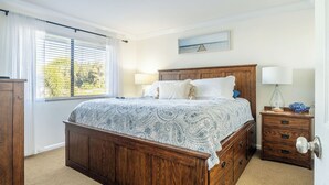 A bedroom with a wooden bed, two bedside tables, a nightstand, and a window with blinds. - Lakefront Condo in Clewiston •Heated Pool•Fishing Paradise •Sleeps 4 (Clewiston)
