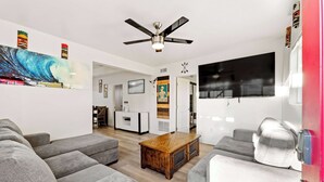 A modern living room with grey sofas, a wooden coffee table, and a ceiling fan.
