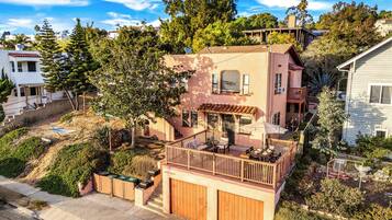 Una casa a due piani con un balcone, un garage e un giardino curato.