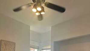 Un salon comprenant un canapé, une table basse, un téléviseur et un ventilateur de plafond.