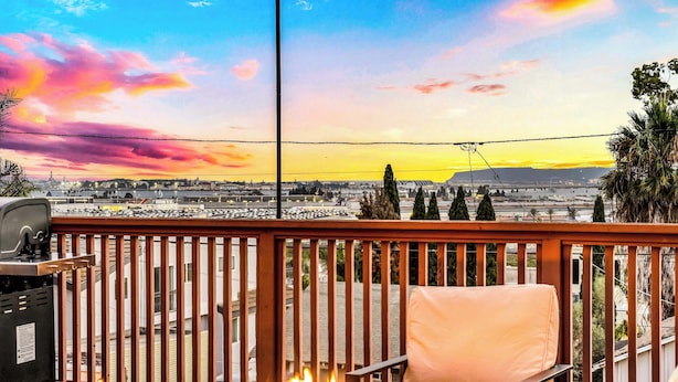Un balcon agrémenté d’un foyer, d’un barbecue et offrant une vue sur le paysage urbain au coucher du soleil.
