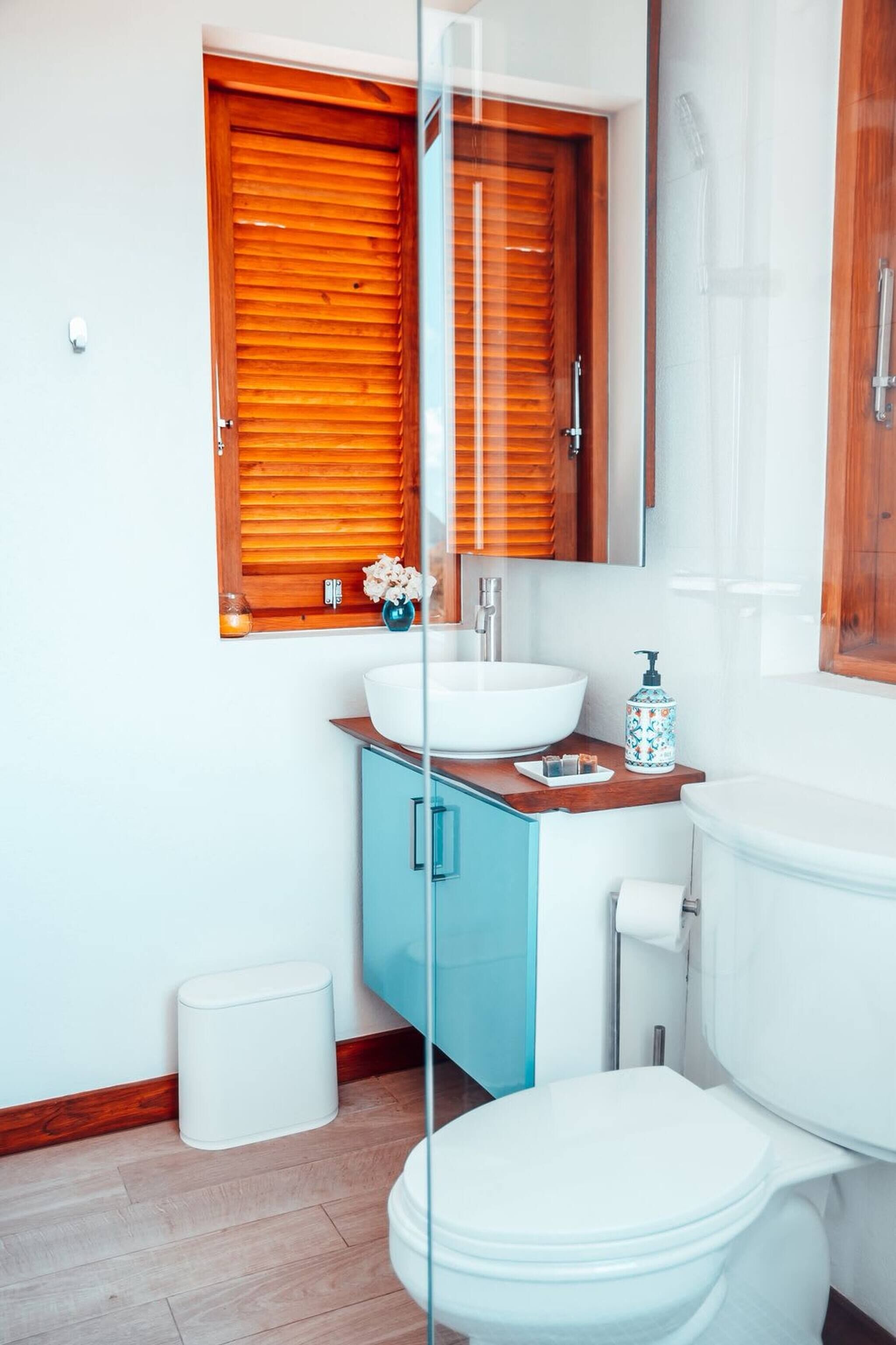 A bathroom with a white toilet, a wooden vanity with a white sink, and a glass shower enclosure.