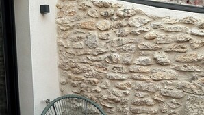 Eine Steinmauer mit einem grünen Drahtstuhl und einer schwarzen Tür.