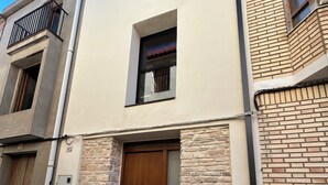 Ein zweigeschossiges Gebäude mit einer Stein-Fassade, einer Holztür und einem kleinen Fenster.